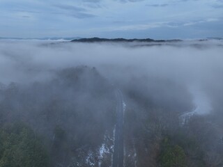 Aerial view of a rural road and village covered in morning fog and clouds in Japan
