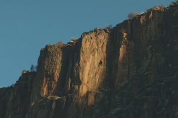 Person climbs rugged rock face at sunset, embracing summer vacation adventure in the great outdoors