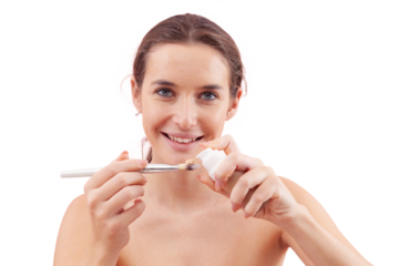 Smiling young woman with natural skin holding foundation pump bottle, dispensing product directly onto makeup brush. Skincare and beauty routine concept. Isolated on white, clean and minimal look.