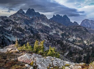 Mountainous landscape featuring jagged peaks, rocky terrain, and scattered trees