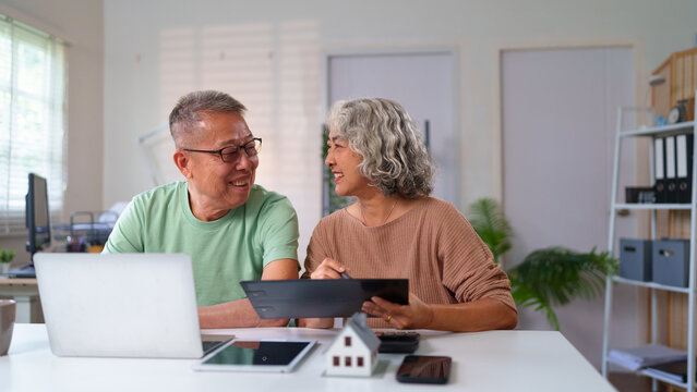 Happy Asian Older Couple Planning Retirement at Home with Laptop and Tablet, Enjoying Relaxing Time Together, Senior Lifestyle and Home Financial Planning