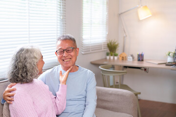 Obraz premium Loving Asian Older Couple Embrace on Sofa in Home Living Room Elderly Romance and Retirement Happiness Senior Moment Togetherness and Home Sweet Home Concept