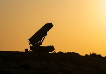 Silhouette of a missile launcher on a barren hill against a dusky sky