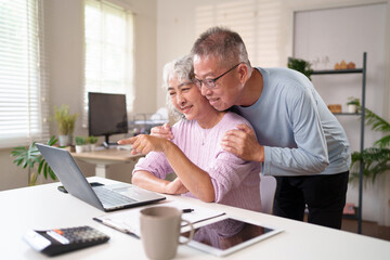 Obraz premium Senior Asian Couple Using Laptop at Home Together Smiling Asian Older People Enjoying Online Time Relaxing at Home Asian Older Relationship Happiness