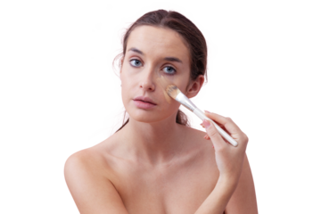 Young woman with natural skin applying foundation with a makeup brush, visible streak on cheek. Skincare and beauty routine concept. Isolated on white background, clean and minimal look