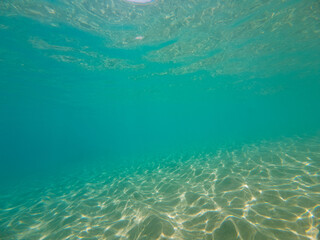 Seabed texture, blue turquoise and white sandy sea floor, water waves reflection, color and light play, top down shot. Summer background concept.