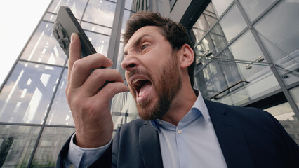 Mad middle-aged Caucasian business man shouting scolding yelling angry to mobile phone conversation...
