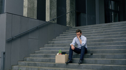 Stressed Caucasian middle aged business man lost job fired work sitting stairs near office building...