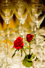 Abstract rendering of red rose buds in a clear glass vase set among clear glass stemware