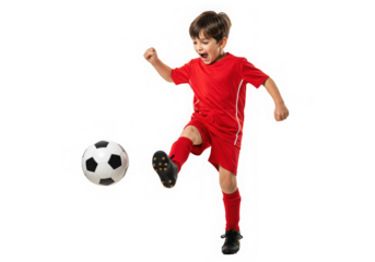 Excited young boy in red sports uniform dynamically kicking a soccer ball with energy and focus.