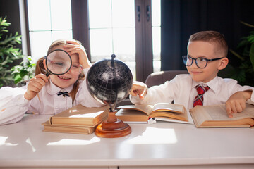 A 7-year-old child in glasses and school uniform poses at the school table indoor