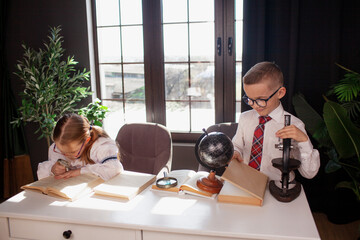 A 7-year-old child in glasses and school uniform poses at the school table indoor