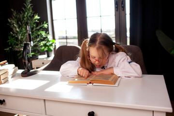 A 7-year-old child in glasses and school uniform poses at the school table indoor