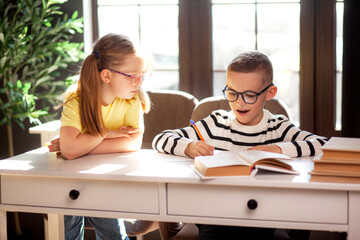 A 7-year-old child in glasses dressed in  school uniform poses at the school table indoor