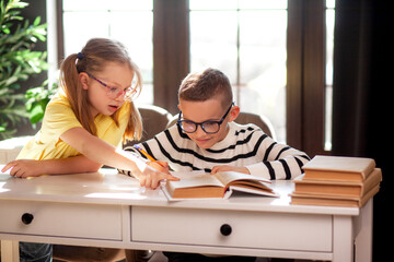 A 7-year-old child in glasses dressed in  school uniform poses at the school table indoor