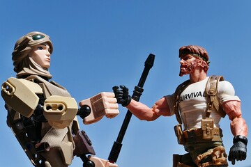 Naklejka premium LEGO Star Wars large action figure of Rey Skywalker in scavenger outfit, ready to shake hand with GI JOE Classified figure of survival instructor Outback, version 2023. Blue skies in background. 
