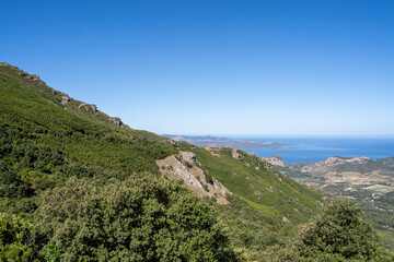 The breathtaking view showcases lush green hills and a stunning coastline all beneath a bright blue sky