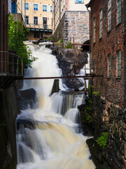 Waterfall cascading past an old industrial building in Mölndal, Sweden showcasing unique architecture and natural beauty