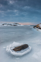 Frozen sea landscape near Gothenburg, Sweden at dusk showcasing ice formations and rocky shores