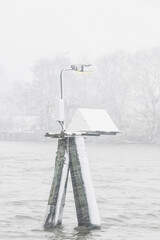 Lamp post standing tall in a snowy river during a heavy snowfall in Sweden captures a serene winter moment