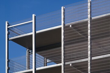 Modern parking garage featuring metal mesh facade and clear blue sky