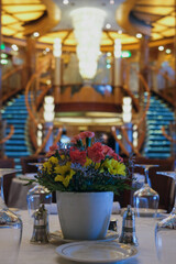 Formal and elegant ocean view dining room restaurant onboard luxury cruiseship or cruise ship liner with set tables in Art Deco interior design style and ceiling ambient lighting