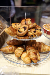 fuente de dos niveles con bollería con caracolas con pepitas de chocolate, cruasanes de mantequilla y hojaldrados en una pastelería artesanal 