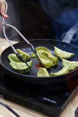 chef cocinando pasta fresca en una sartén y manipulándola con la pinza de cocina