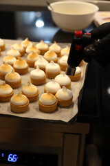 repostero profesional flambeando con un soplete pastelitos de tartaleta de hojaldre y crema...