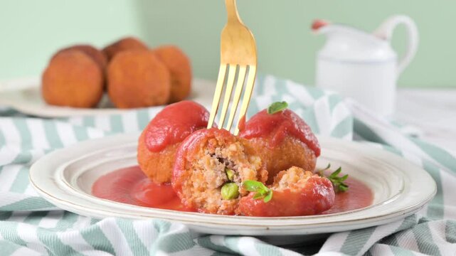 Close-up of hands breaking Sicilian arancini with rice, cheese and herbs. Crispy texture and savory filling. Traditional Italian street food. High quality FullHD footage
