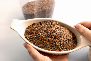 Healthy uncooked raw flax seeds in a bowl in women's hands. High quality photo