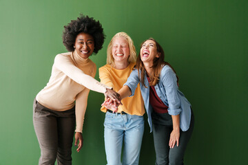 Happy Multicultural Friends Sharing a Joyful Moment Laughing Together Against a Solid Green Backdrop