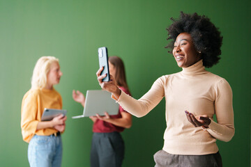 Diverse Young Adults Using Technology with Focus on Smiling Woman Holding Smartphone in Bright...