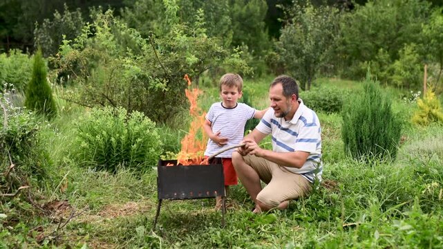 father and son making fire outdoors. Fire safety. Forest fire. Time with kids, outdoor recreation, barbecue picnic. Father's Day