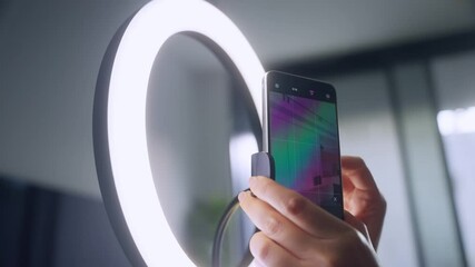 Close up on ring light for vlogging hand setting up phone on stand for video. Before recording social content woman preparing mobile phone on dedicated rig for live stream and selfie video filming