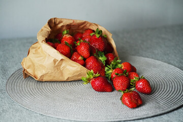 Ripe strawberry in paper bag on table close-up