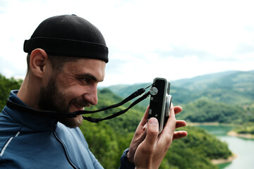Side portrait of a man preparing to take a photo with an instant camera, enjoying the scenery at...