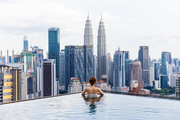 A woman in a bikini enjoys the rooftop pool and skyscrapers in a modern city