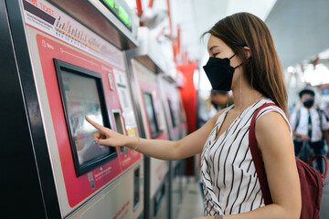 Woman buying a subway ticket on the ticket machine in the station