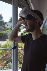 Obraz premium Young Man in a casual tshirt using virtual reality glasses, wearing new generation vr headset playing at home and smiling.