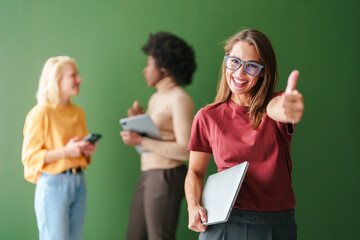 Confident Young Woman Holding Tablet with Diverse Group of Adults Engaged in Technology on Green Background