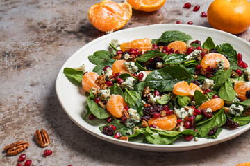 An appetizing festive salad of fresh spinach, tangerine, pomegranate and pine nuts on a plate. 