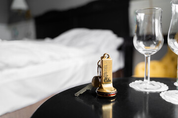 A cozy and inviting hotel room elegantly featuring a key, shimmering wine glasses, and a neatly...