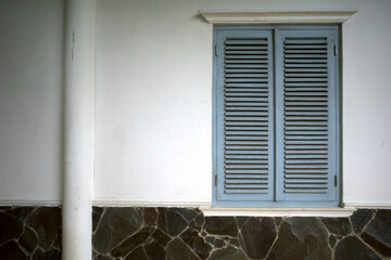 A weathered light blue old vintage window on white wall