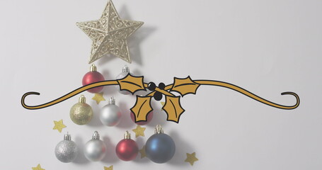 Displaying gold holly and berry banner on tabletop, with gold star ornament, baubles and confetti