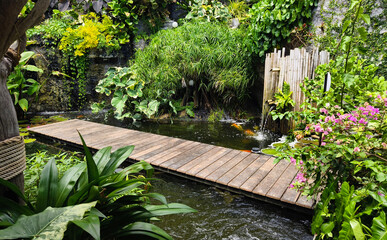 A charming wooden bridge spans a tranquil pond in a serene garden