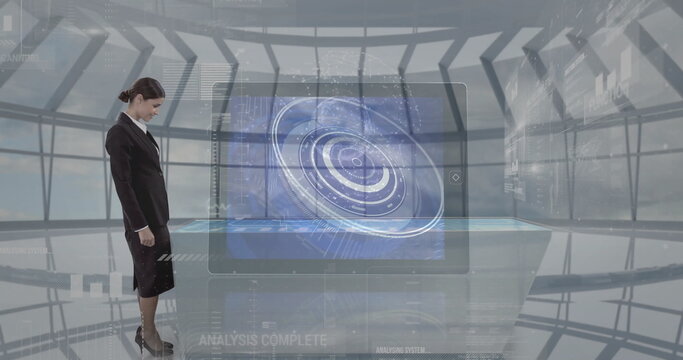 Standing businesswoman examining holographic tabletop display in control center, copy space - Powered by Adobe