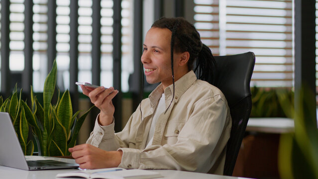 American business man male businessman guy at desk talking mobile phone microphone in office saying smartphone using smart technology dictate commands loudspeaker recording voice mail audio message