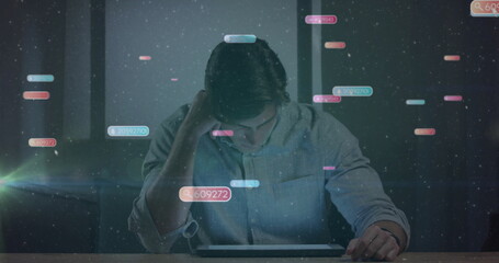 Leaning adult man touching temple scanning tablet in dimly lit workstation, with floating data bars