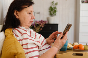 Senior woman having breakfast sitting in bed, drinking tea, enjoying her morning at home. Old lady...
